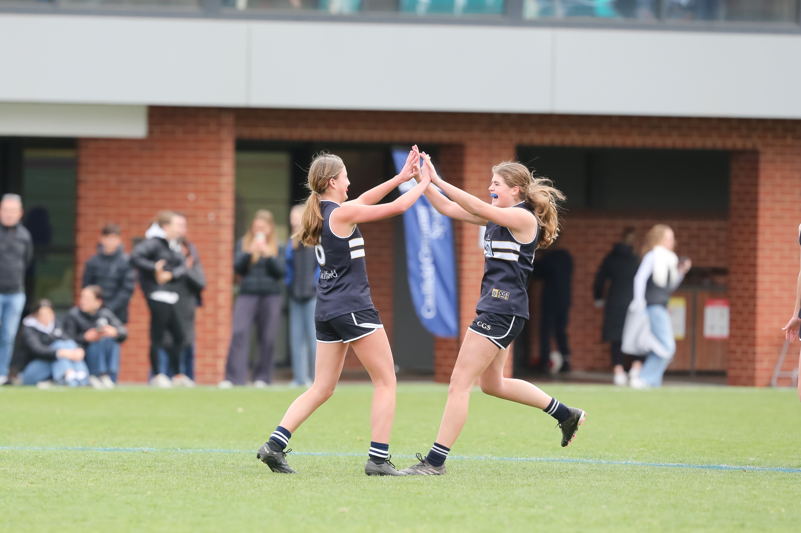 Two girls playing football on a grass field