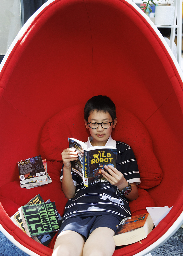 Male student reading a book in a quiet corner of the library.