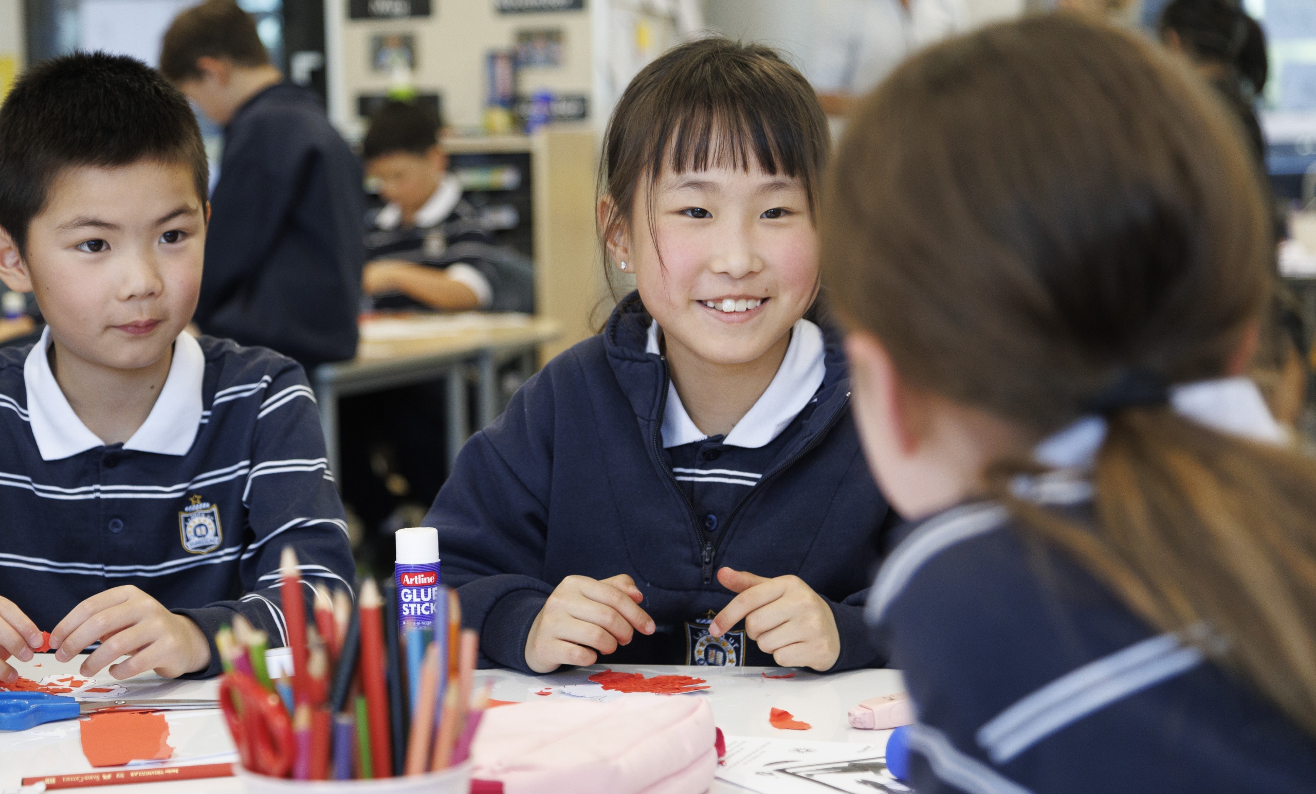 A group of junior school students sitting at a table, engaged in a classroom activity
