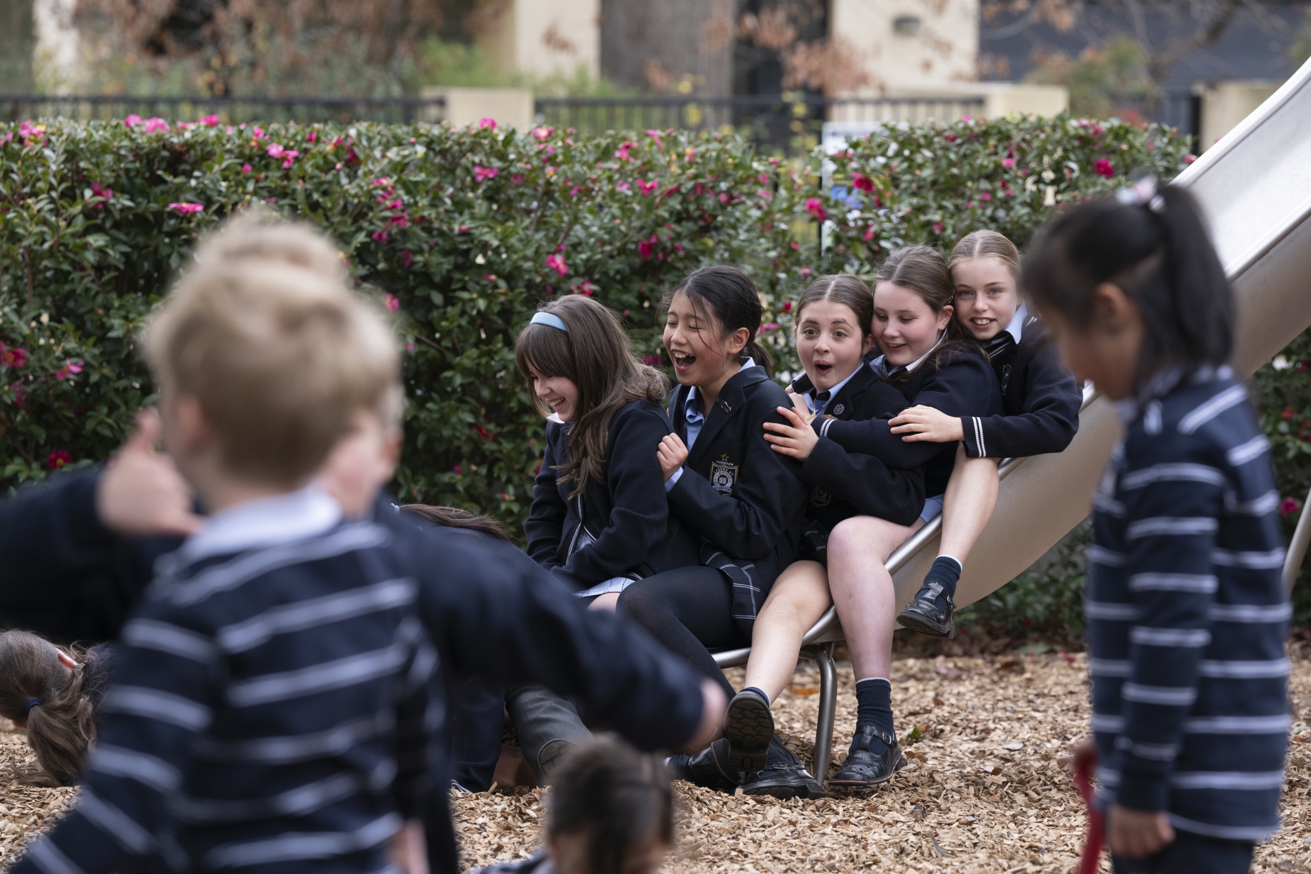 A group of Junior School students sitting on a slide in a playground
