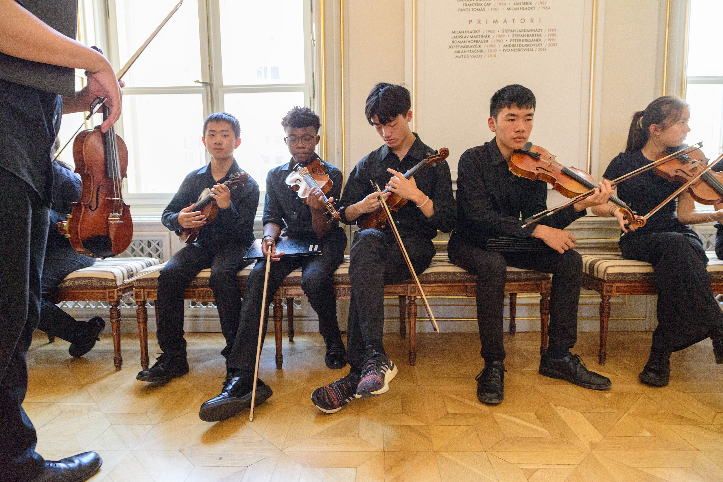 Students sitting on a bench and playing violin