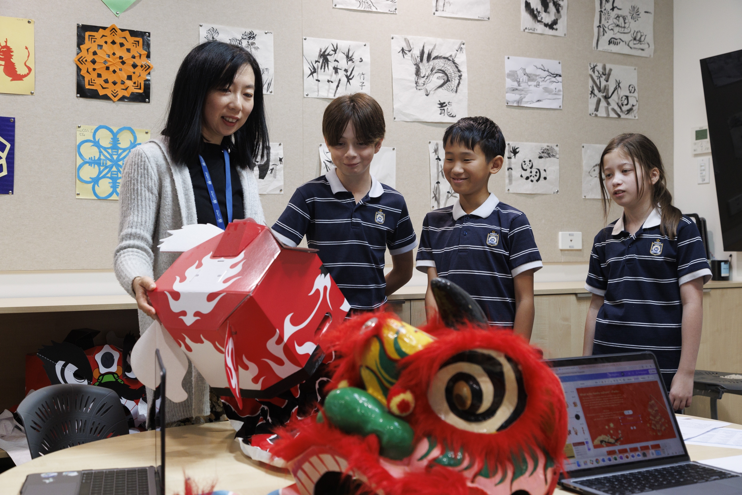 Junior school students and their teacher looking at a project they’ve made during their Chinese class